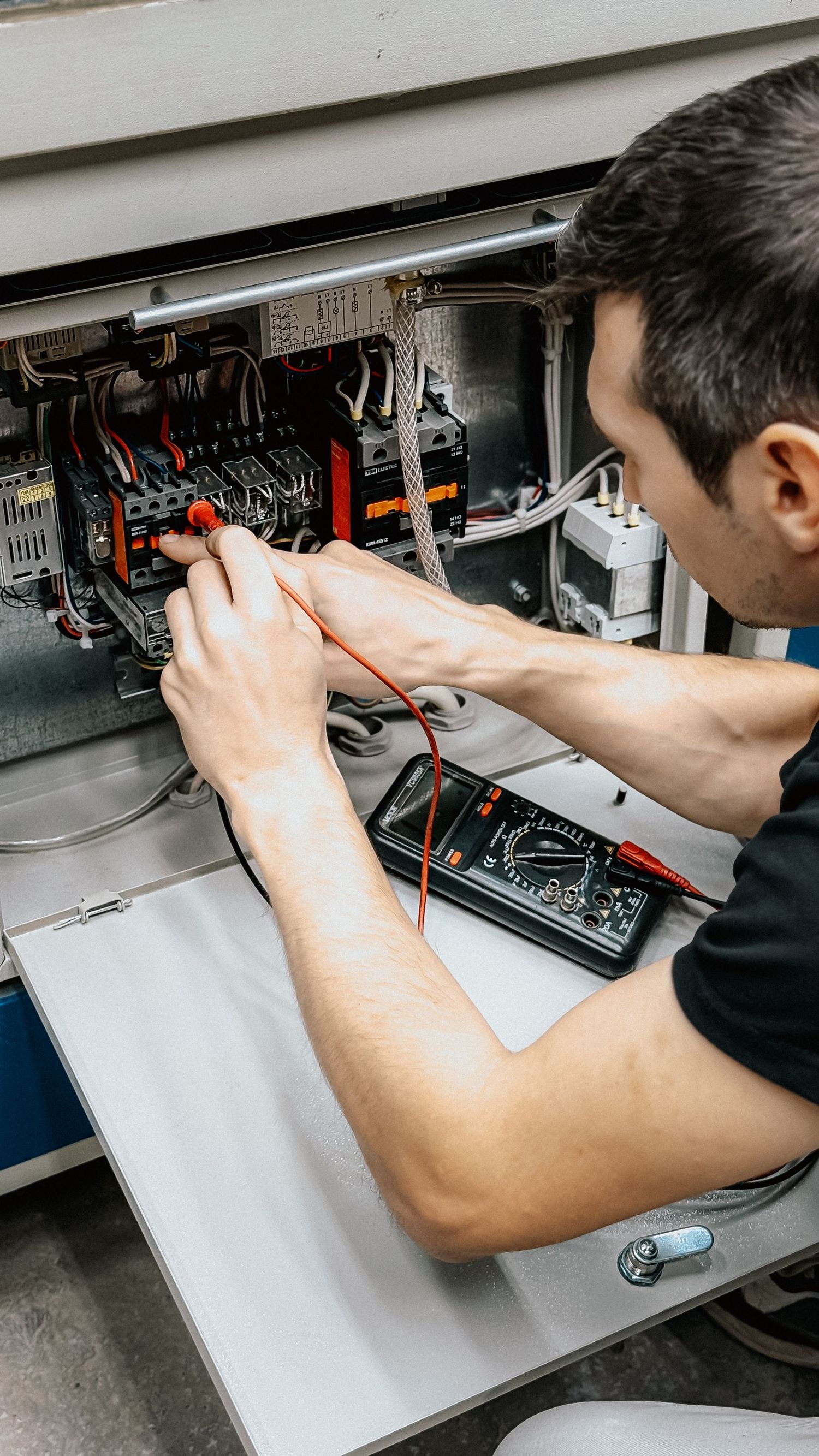 An electrician testing a distribution board with a multimeter